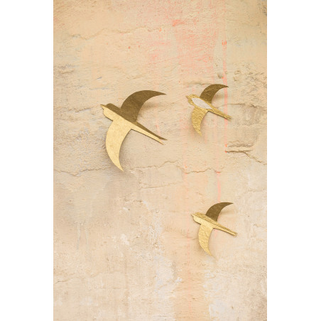 Three pretty golden paper swallows hanging on the wall