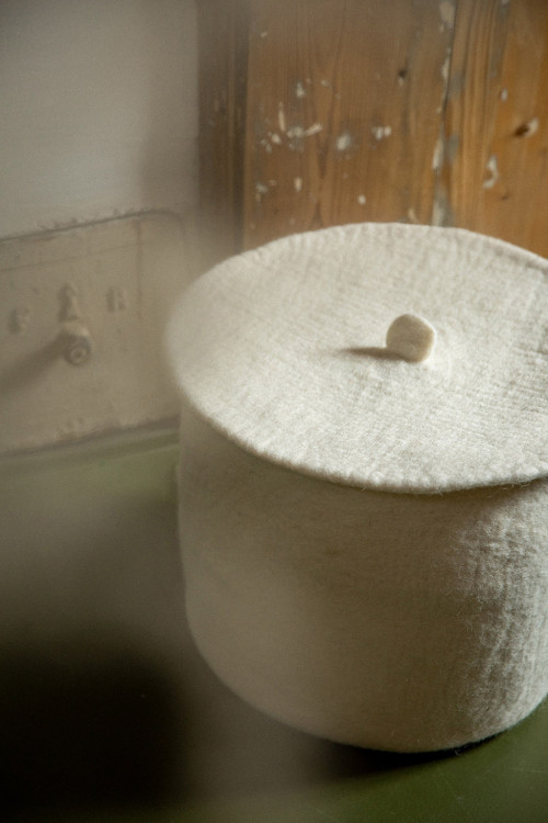 a basket placed on a bench with its lcover for a felted decoration