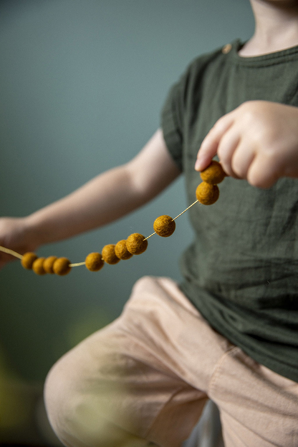 des pompons en feutre sur un fil doré pour créer un guirlande ludique