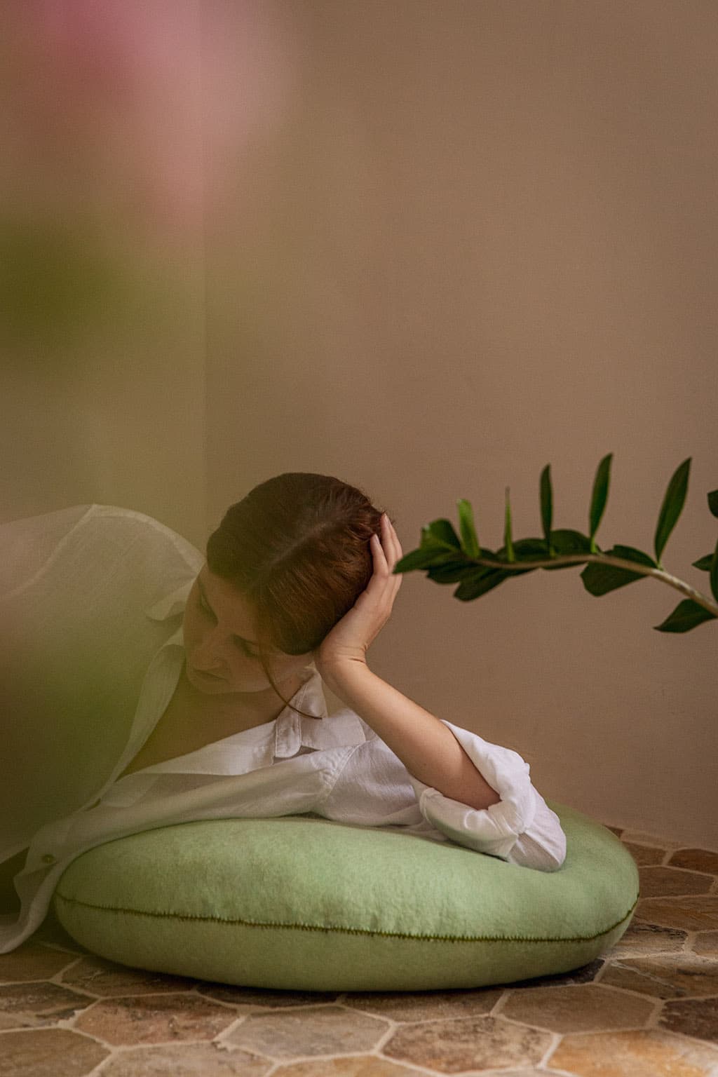 A woman meditating on a round, mint-green felted wool floor cushion