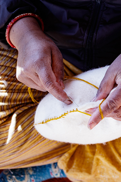 Artisane népalaise en train de faire la couture d'un coussin en laine feutrée