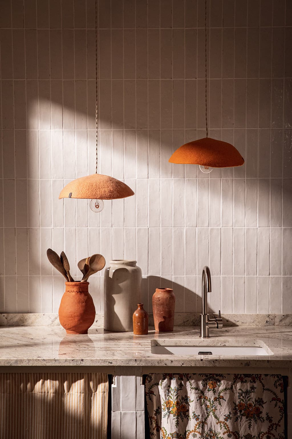 Duo of orange and pink felt pendant lights in a kitchen