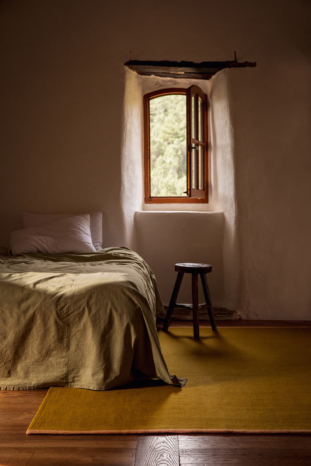 Large rectangular green felted wool rug in a bedroom